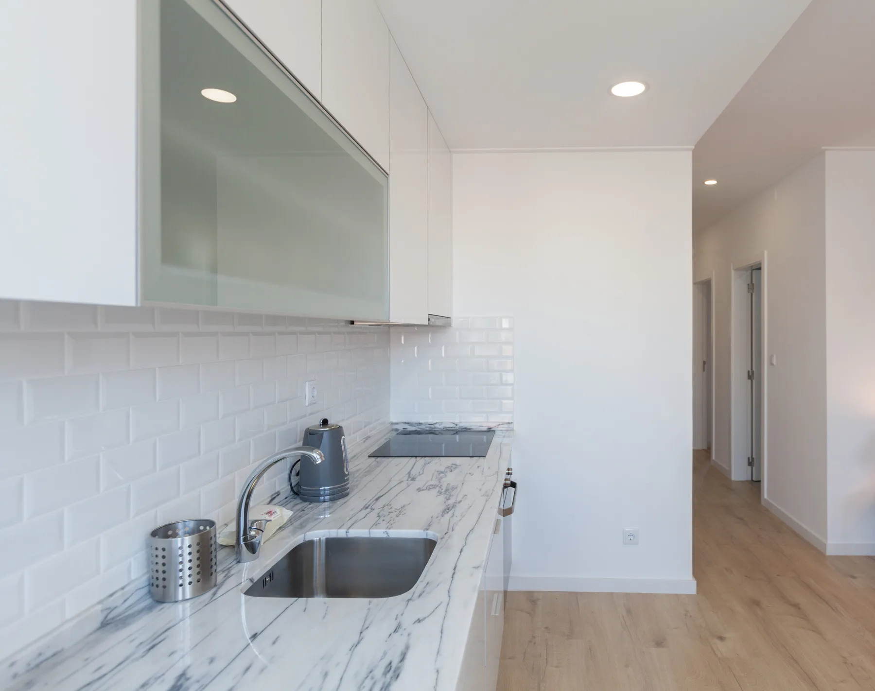 Una cocina moderna con fregadero y encimera junto a un pasillo.
