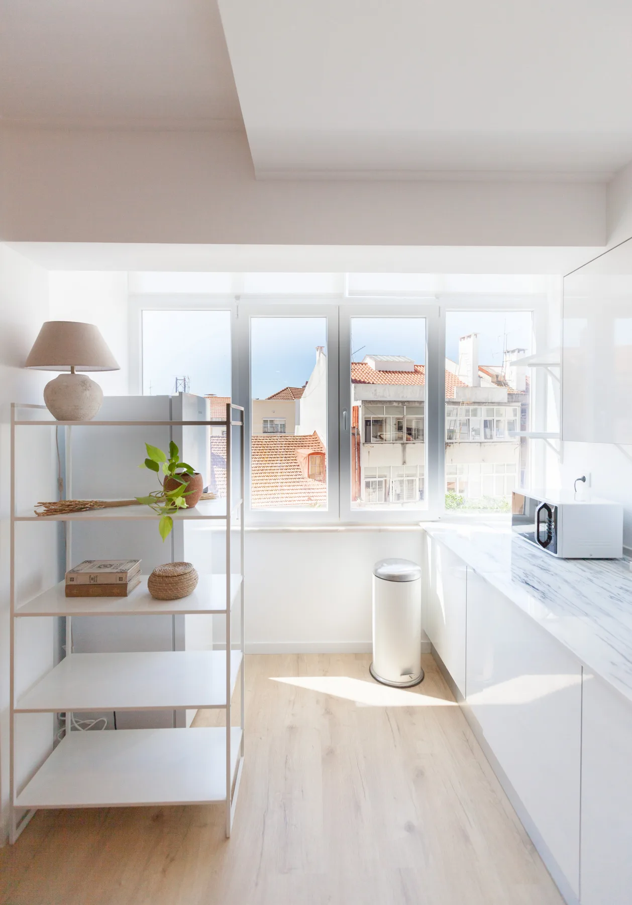 Una cocina luminosa con encimera, estanterías y ventanas grandes.