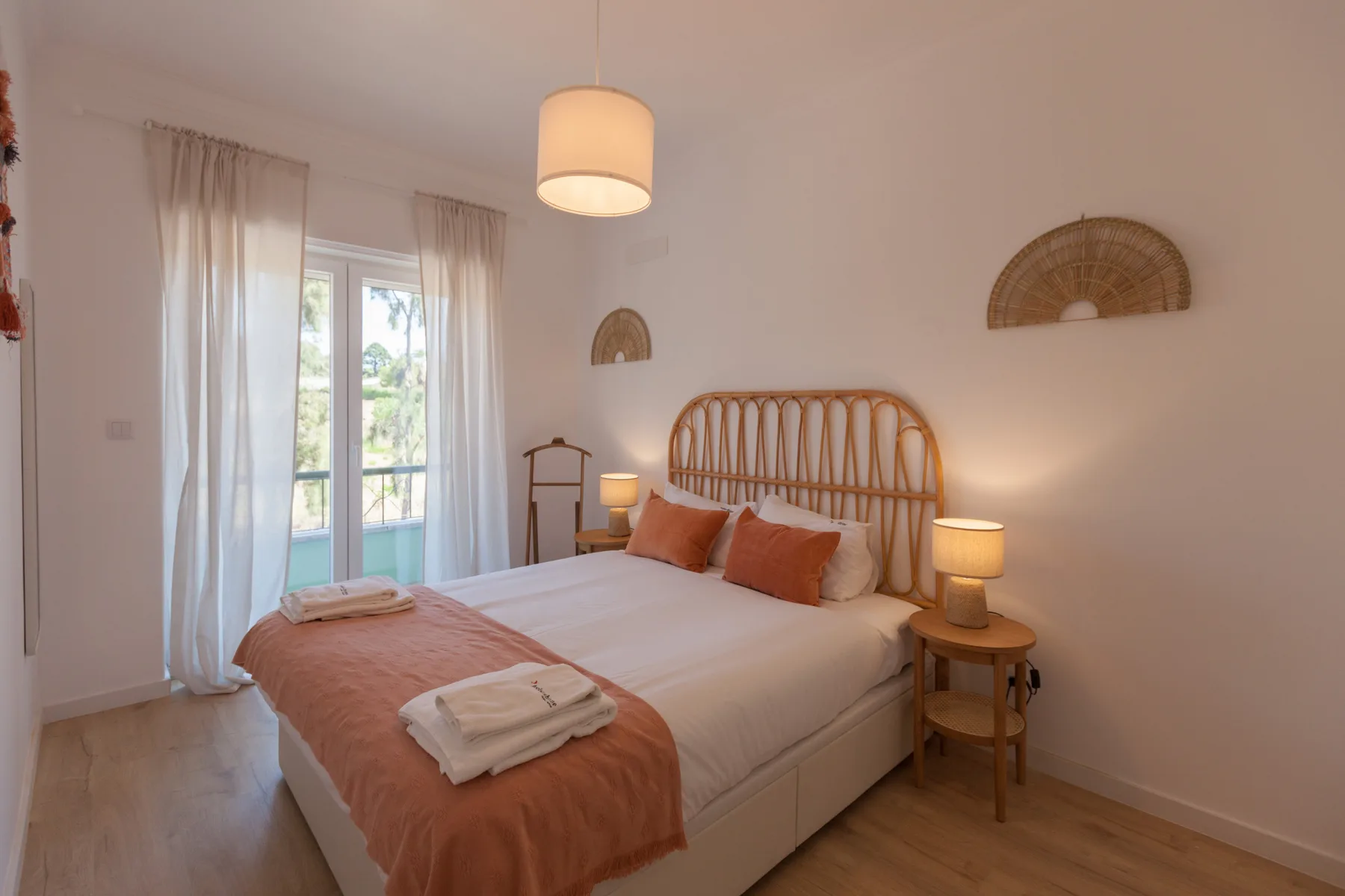 A bedroom with a bed, bedside tables, and a glass door opening to a balcony.