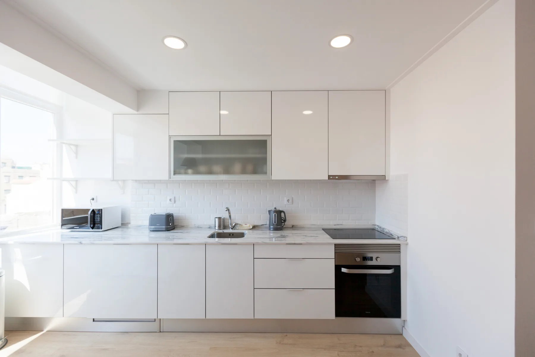 Una cocina luminosa y moderna con armarios blancos y un horno integrado.