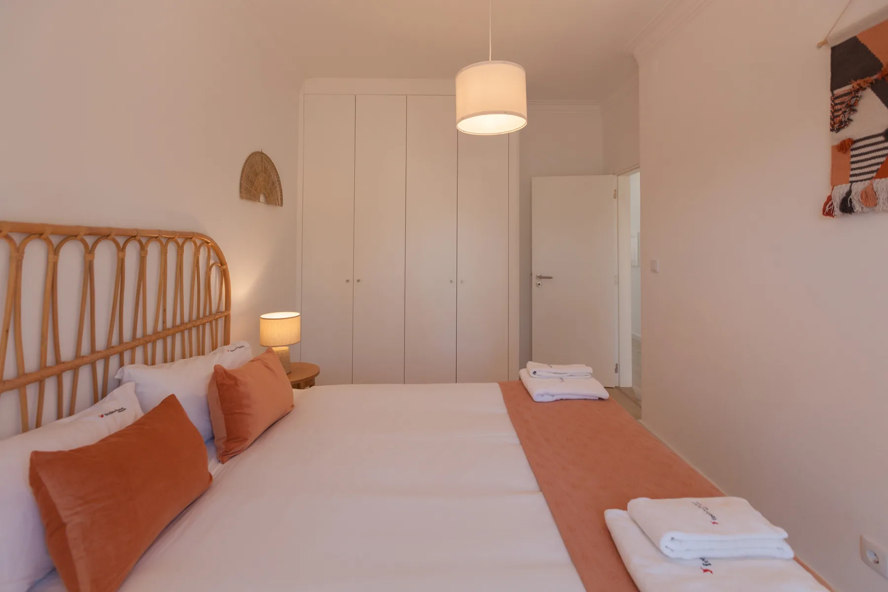 A bedroom with a bed, bedside lamp, and built-in wardrobe.