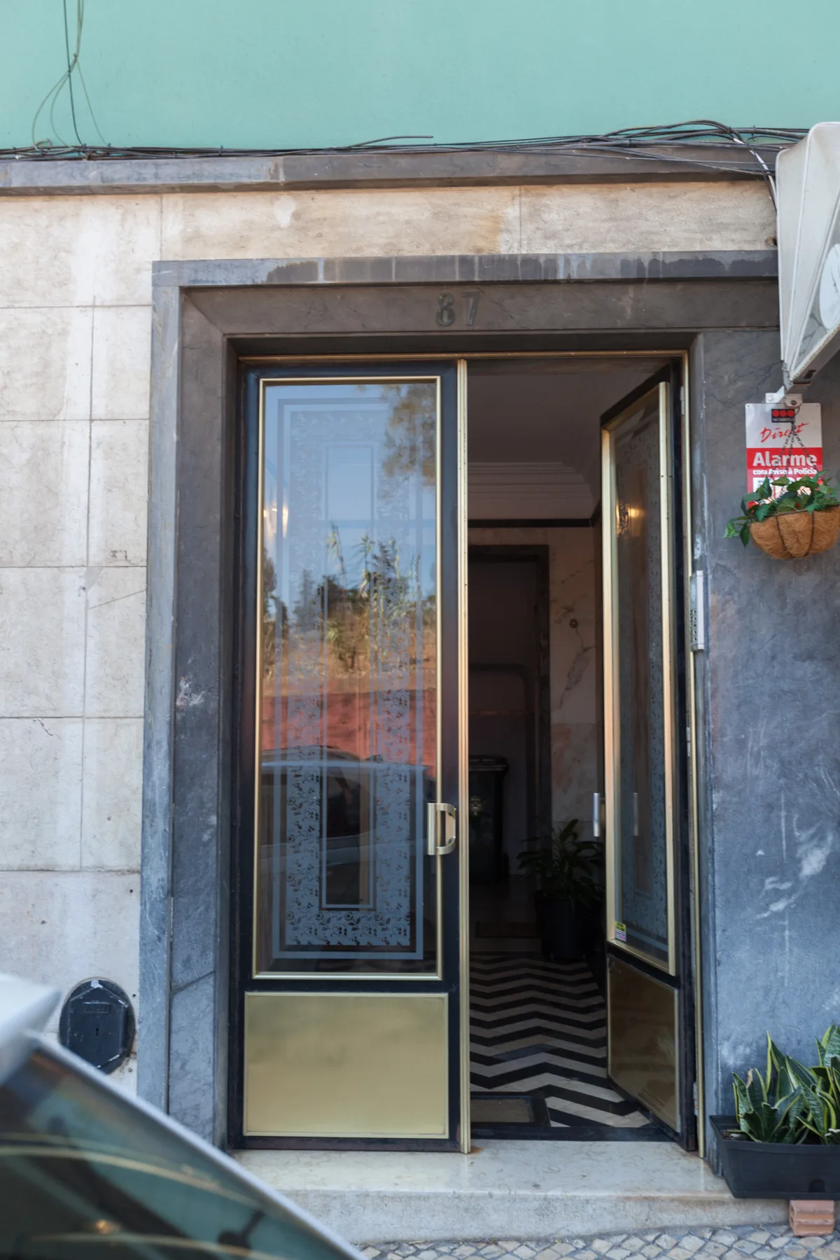 An open entrance door leads into a hallway with a patterned floor.