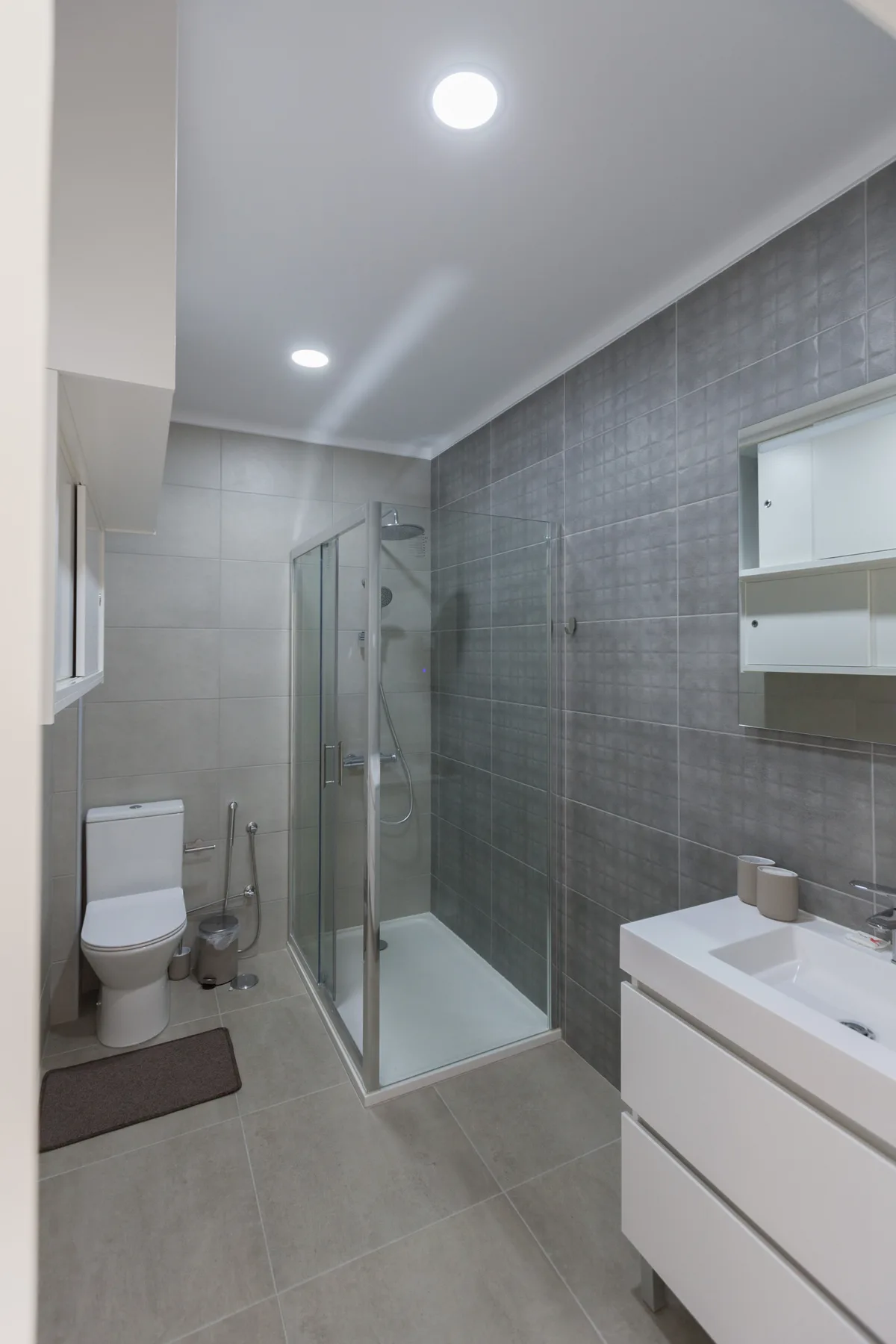 A tiled bathroom with a glass shower, toilet, and vanity.