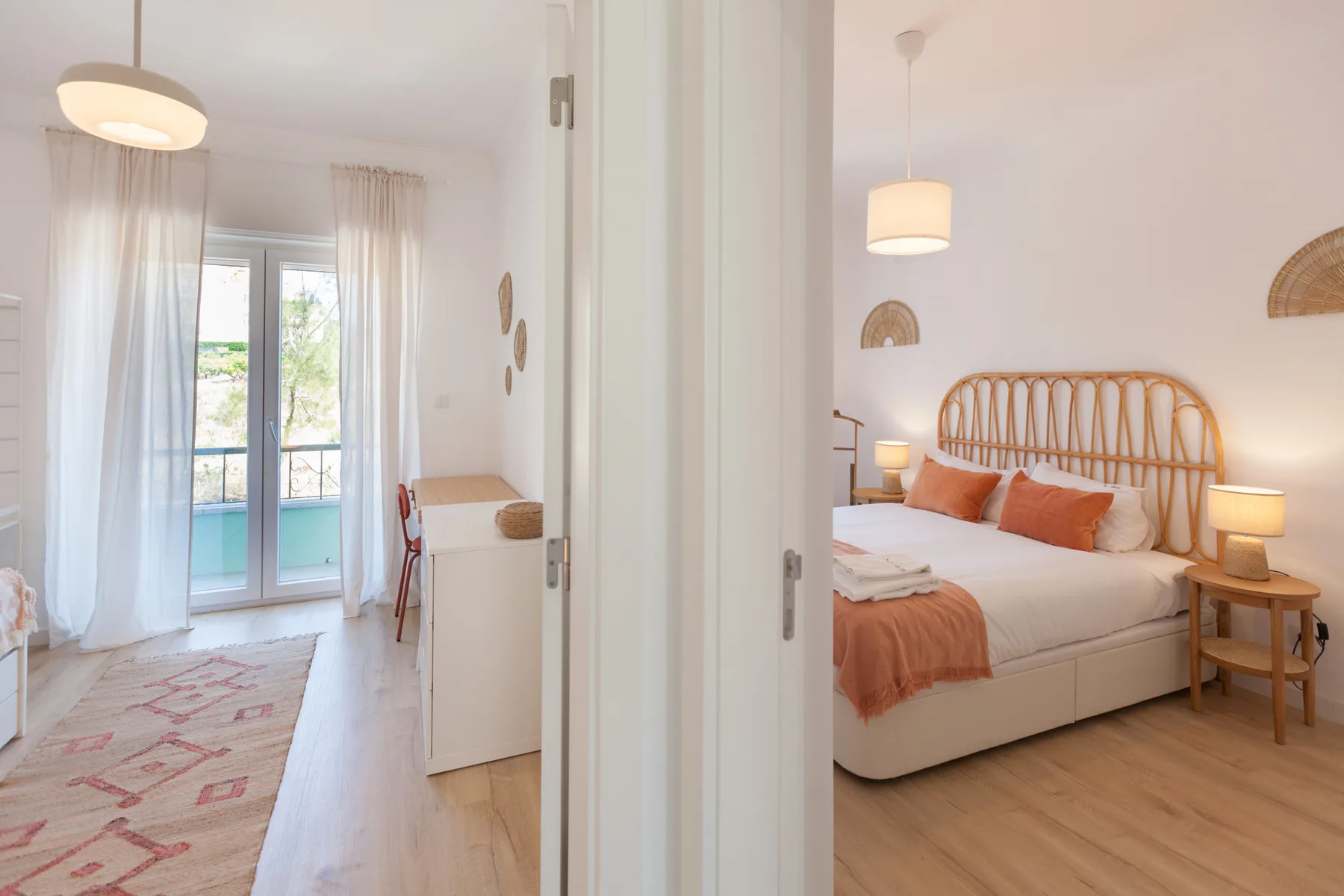 A bright bedroom with a bed, bedside tables, and a balcony visible through glass doors.