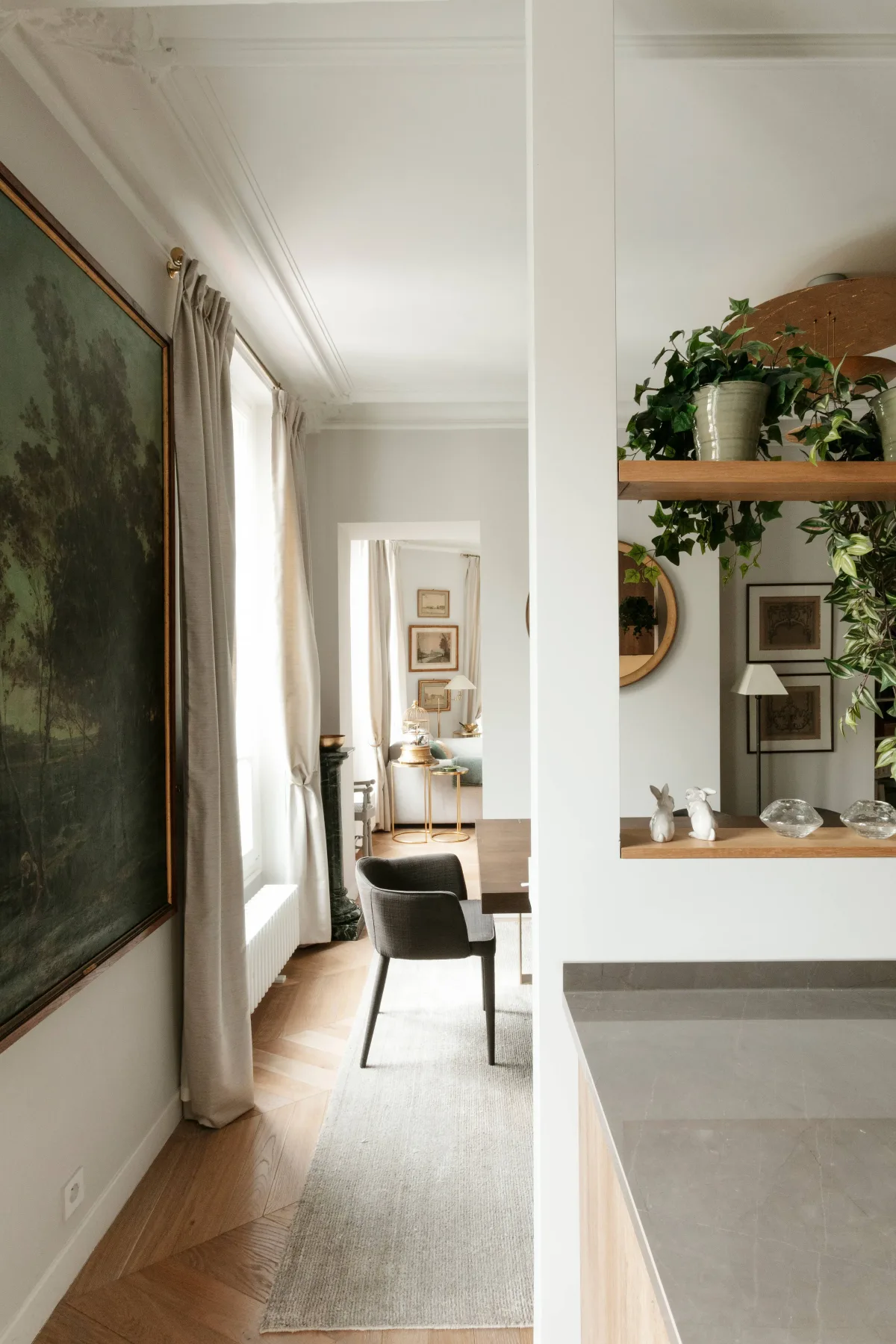 A bright living and dining area with tall windows and a shelf of plants.