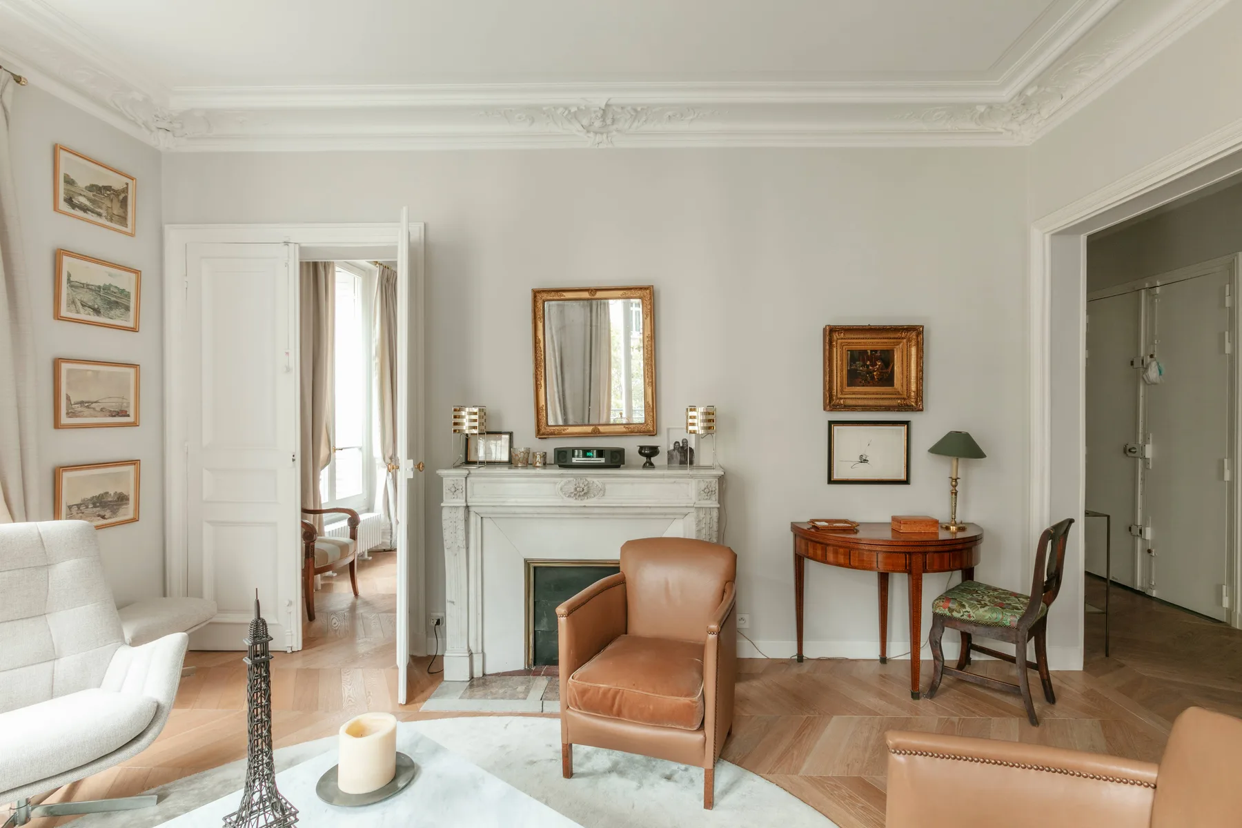 Una sala luminosa con chimenea, sillones y cuadros enmarcados.