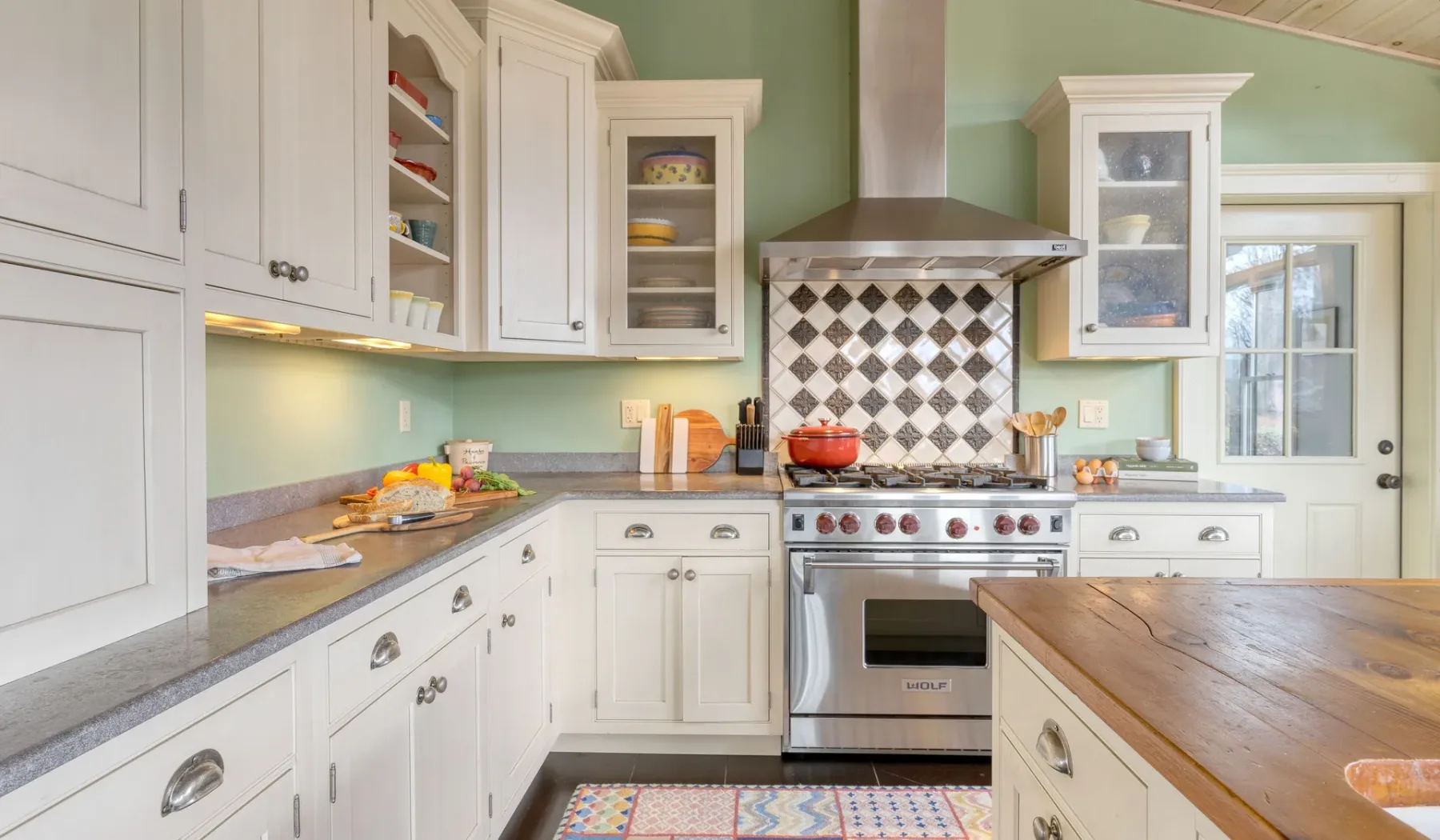 Una cocina con gabinetes blancos, una estufa y un salpicadero de azulejos.