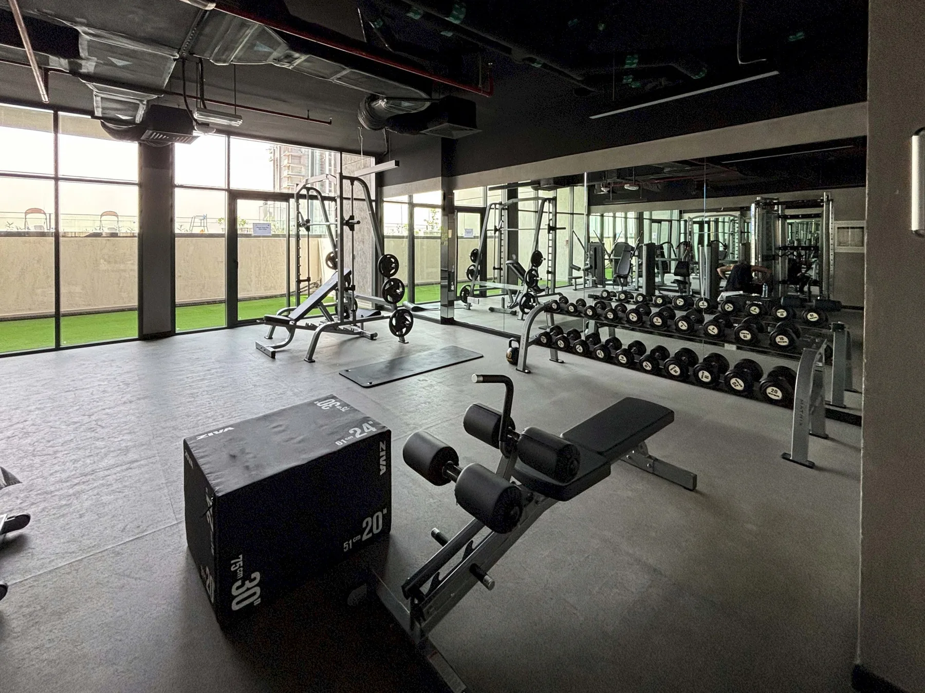 A gym with weight-training equipment and a mirrored wall.