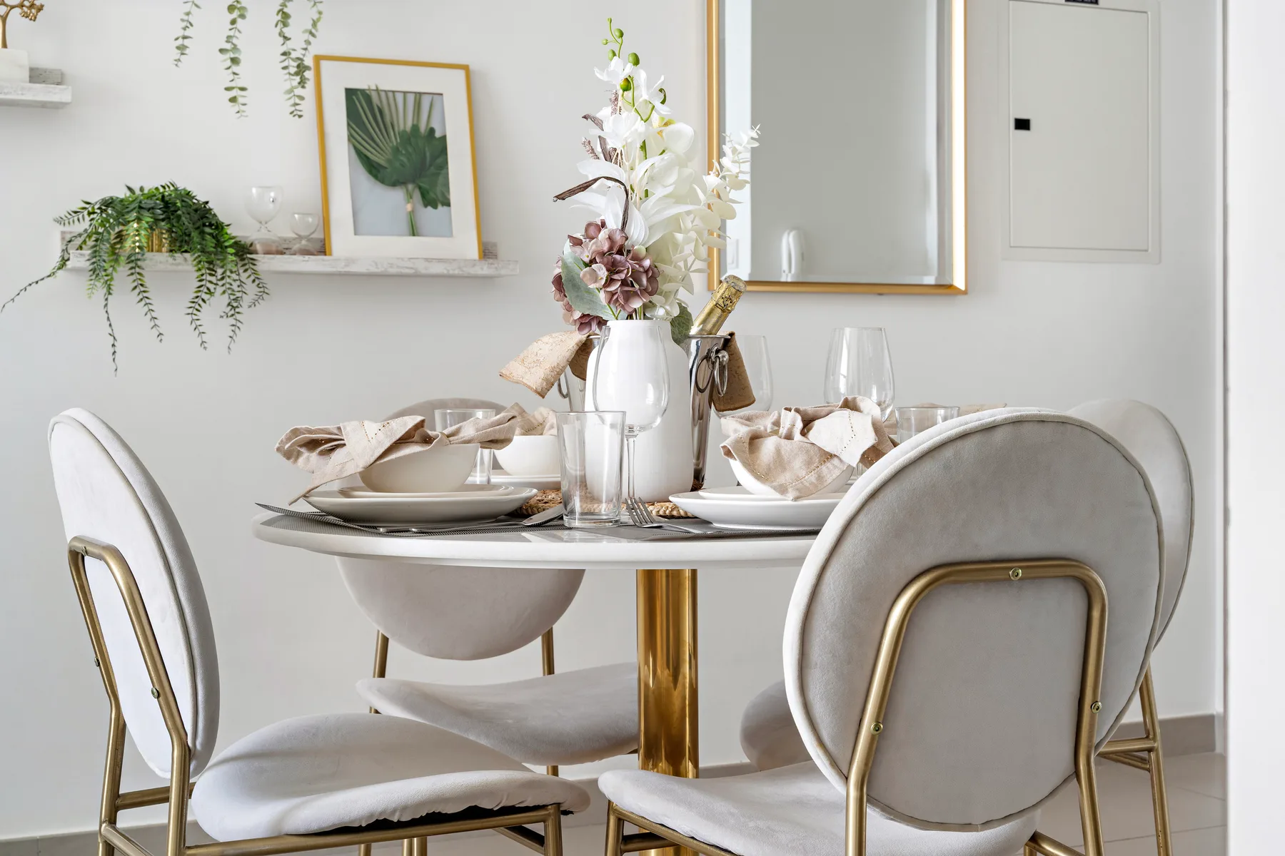 A dining area with a round table set with plates and floral arrangements.