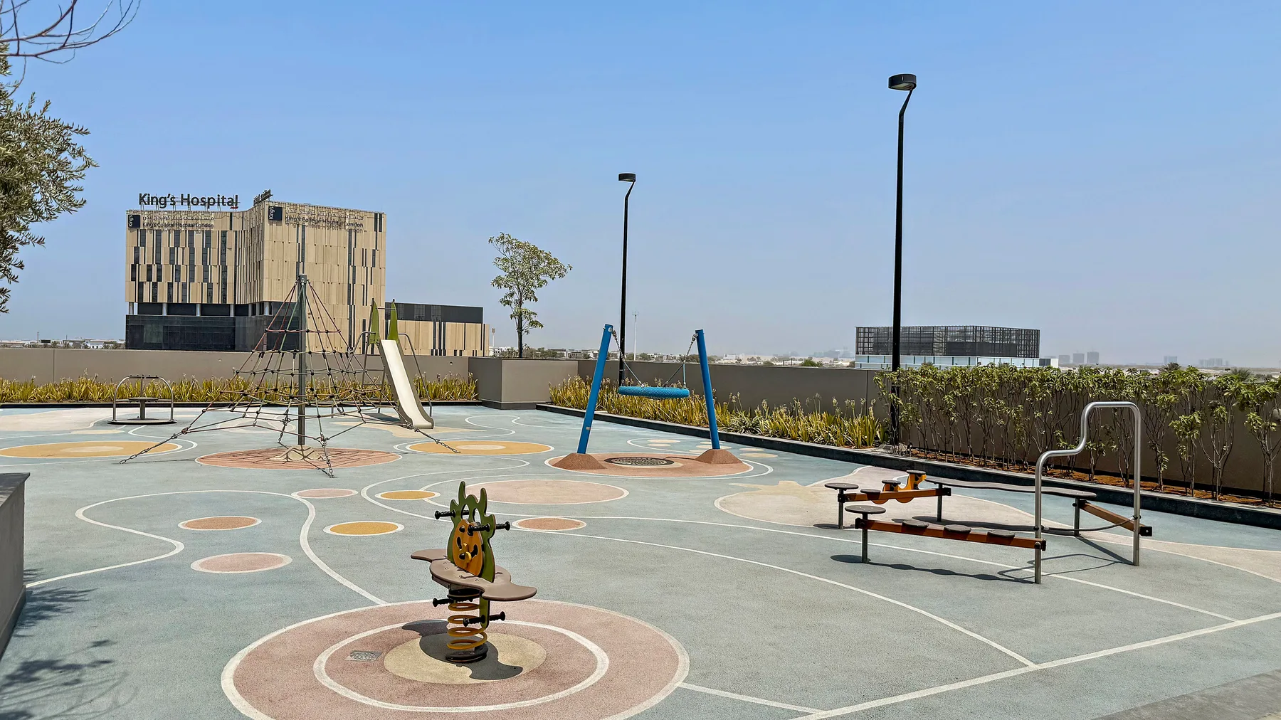 An outdoor playground with colorful markings, swings, and play equipment.