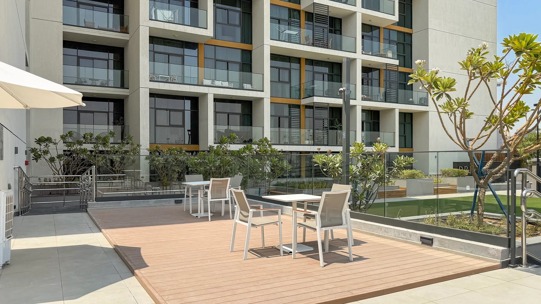 An outdoor seating area with tables beside a modern apartment building.