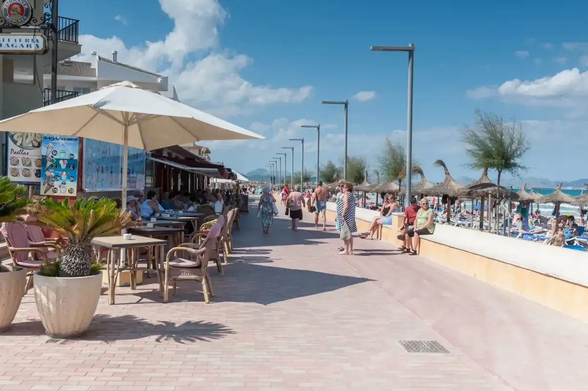 Un paseo junto al mar tiene mesas de café al aire libre junto a la playa.