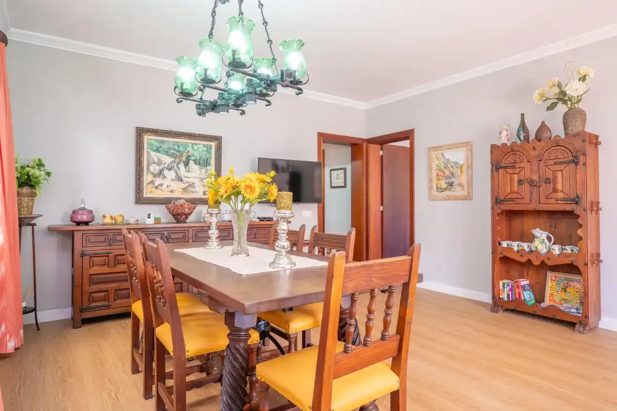 Comedor con una mesa y sillas de madera bajo una lámpara de araña.