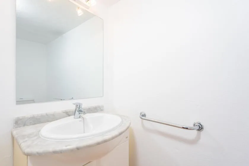 Un lavabo de baño con espejo y barra de apoyo.