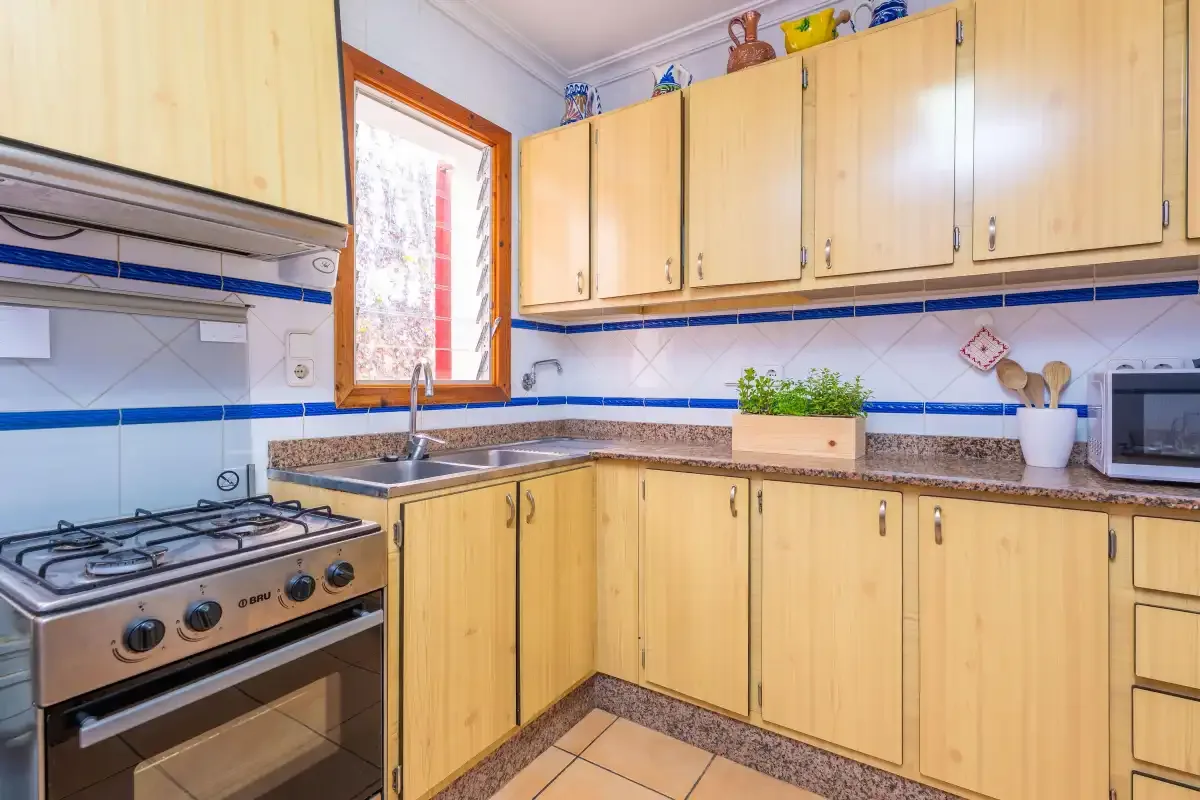 Una cocina con armarios de madera clara, encimera y fogones de gas.