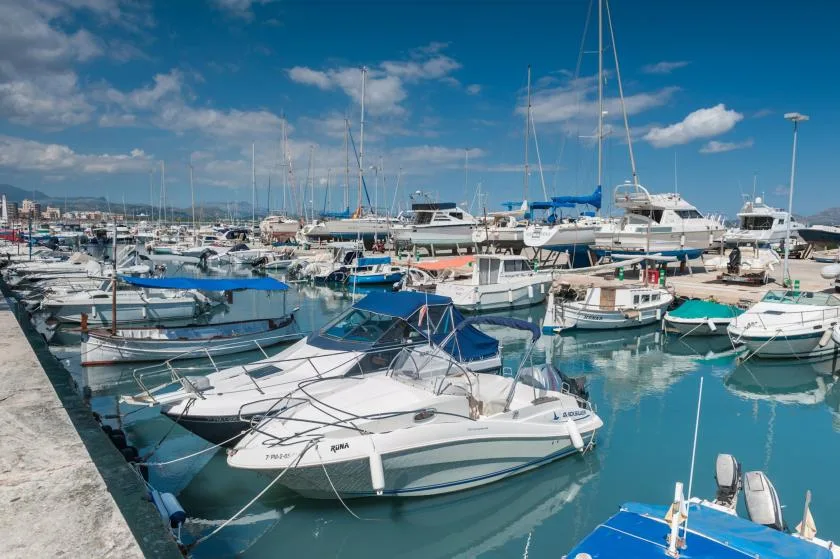 Un puerto deportivo lleno de barcos y veleros amarrados en aguas azules tranquilas.