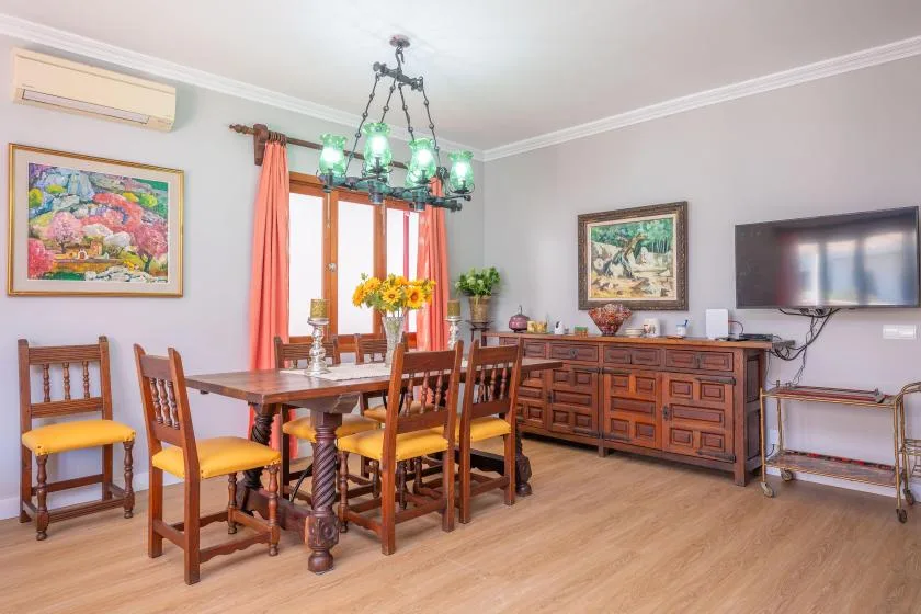 Un comedor con una mesa de madera y sillas bajo una lámpara colgante.