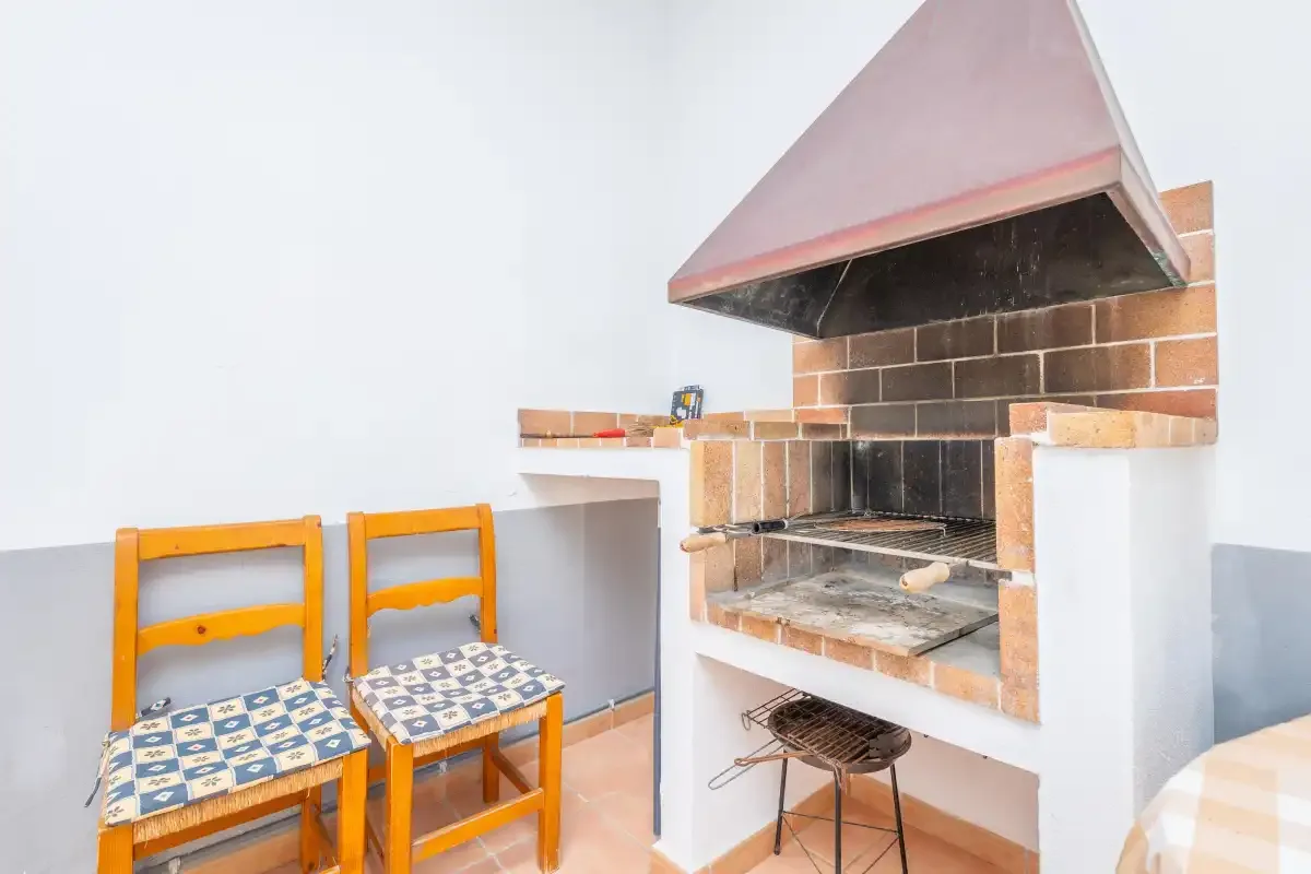 Una parrilla está junto a dos asientos de madera en una luminosa zona de cocina interior.