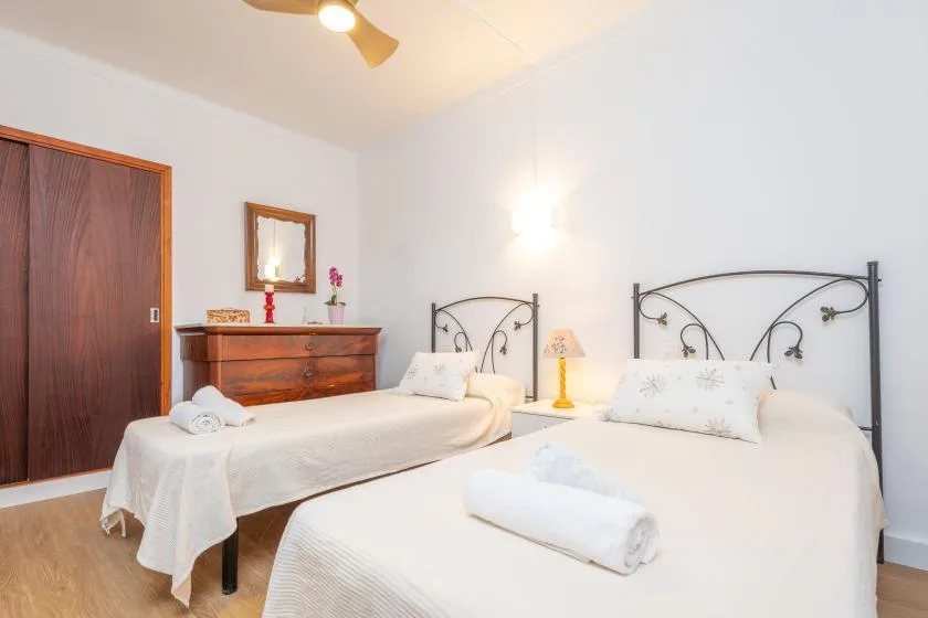 Un dormitorio luminoso con dos camas y una cómoda de madera.
