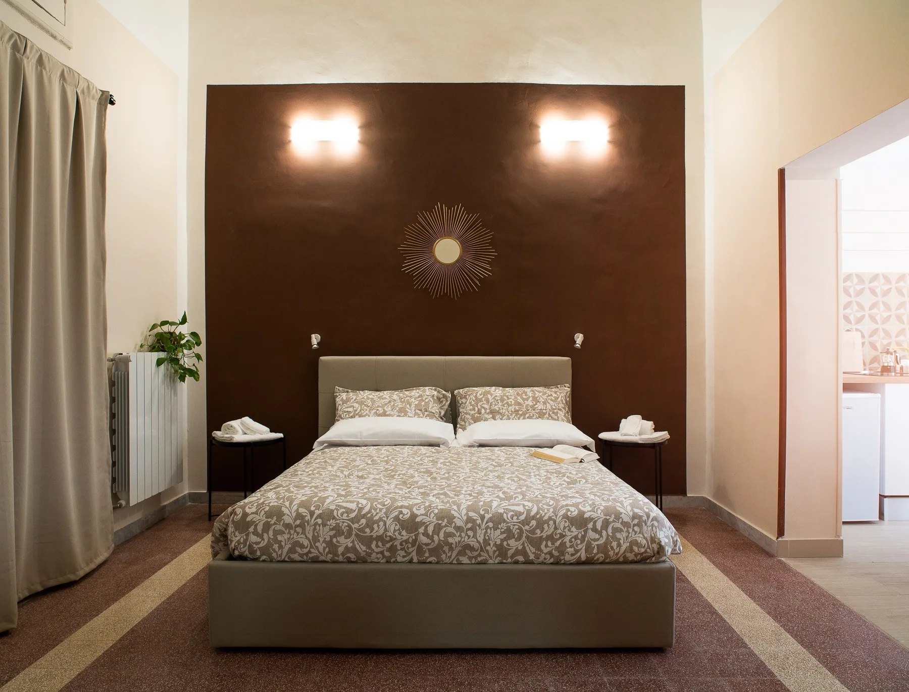 A bedroom with a double bed centered against a dark accent wall.