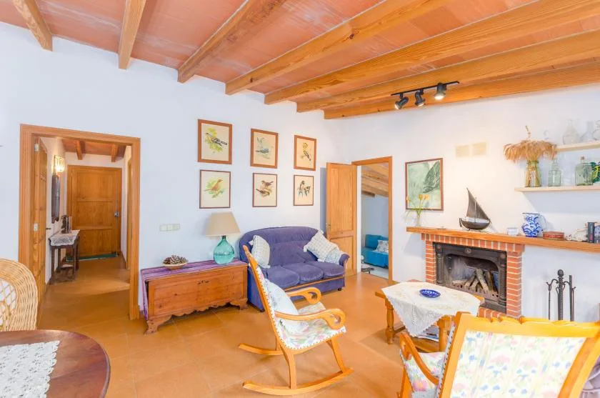 A living room with seating around a fireplace and a wooden-beam ceiling.