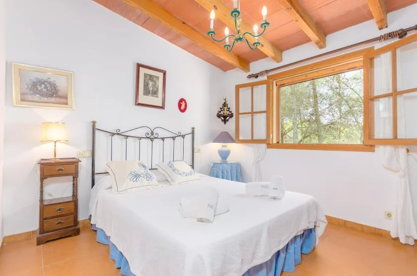 A bedroom with a double bed, bedside tables, and a large window.