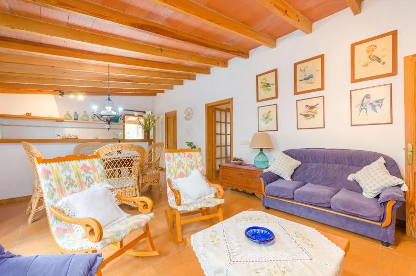 A living room with seating, framed artwork, and exposed wooden ceiling beams.