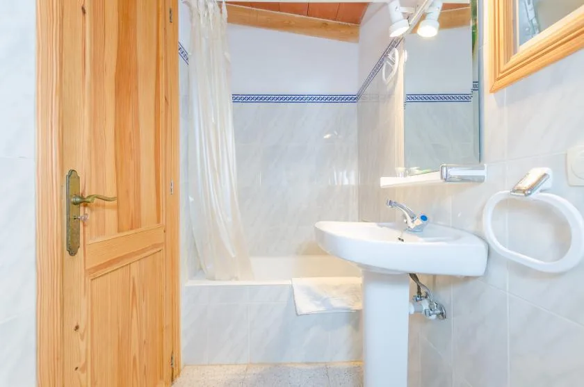 A bathroom with a sink and a curtained bathtub.