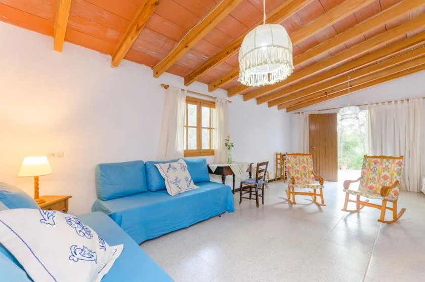 A bright living room with blue seating and two wooden rocking chairs.