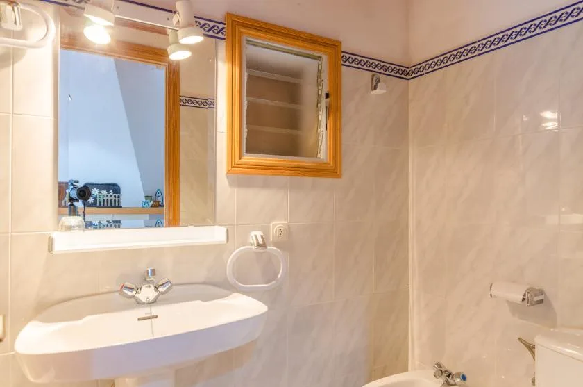 A tiled bathroom with a sink, mirror, and toilet.