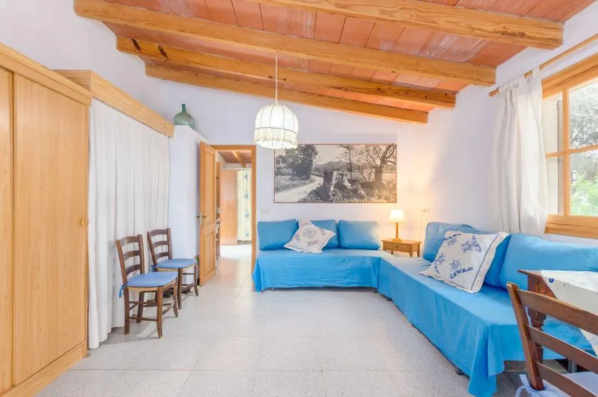 A bright living room with blue seating beneath exposed wooden ceiling beams.