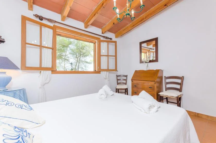 A bedroom with a large bed, wooden furnishings, and an open window.