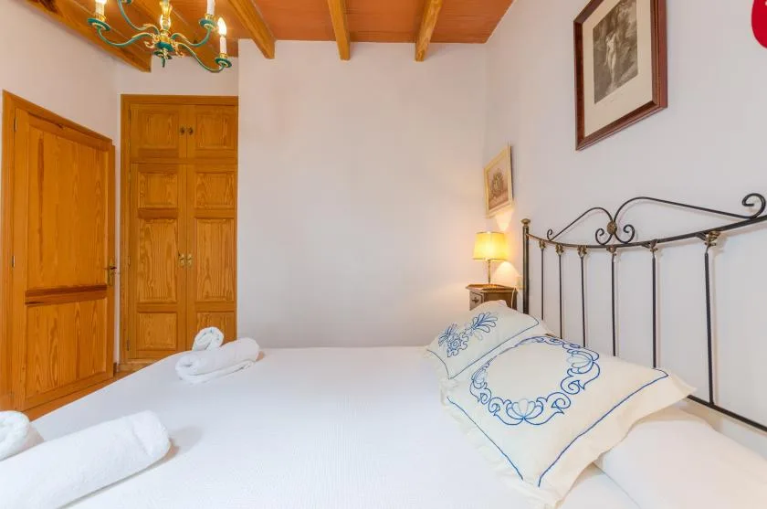 A bedroom with white bedding, a decorative metal headboard, and wooden doors.