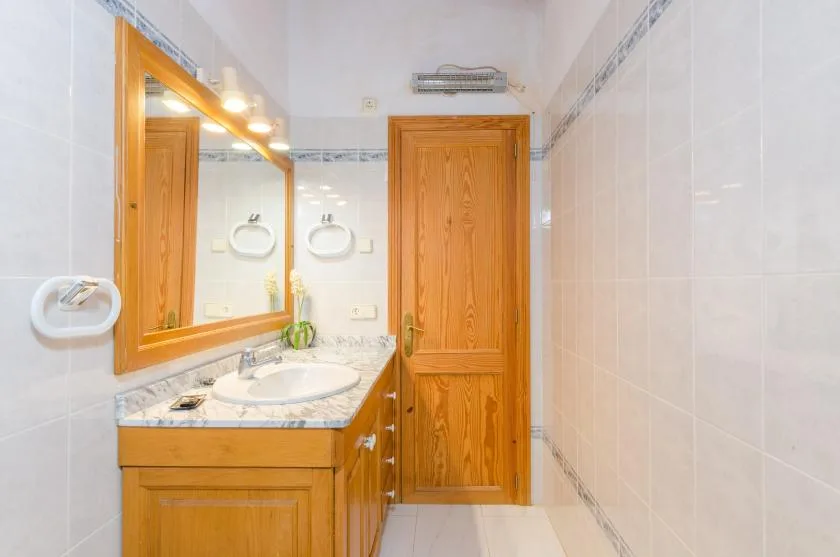 A bathroom with a wooden vanity, sink, and large mirror.