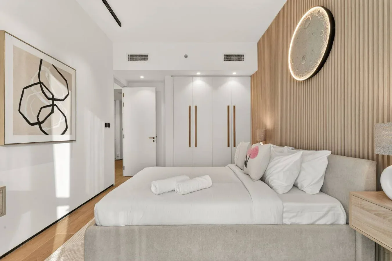 Un dormitorio con una cama bien tendida y arte abstracto en la pared.