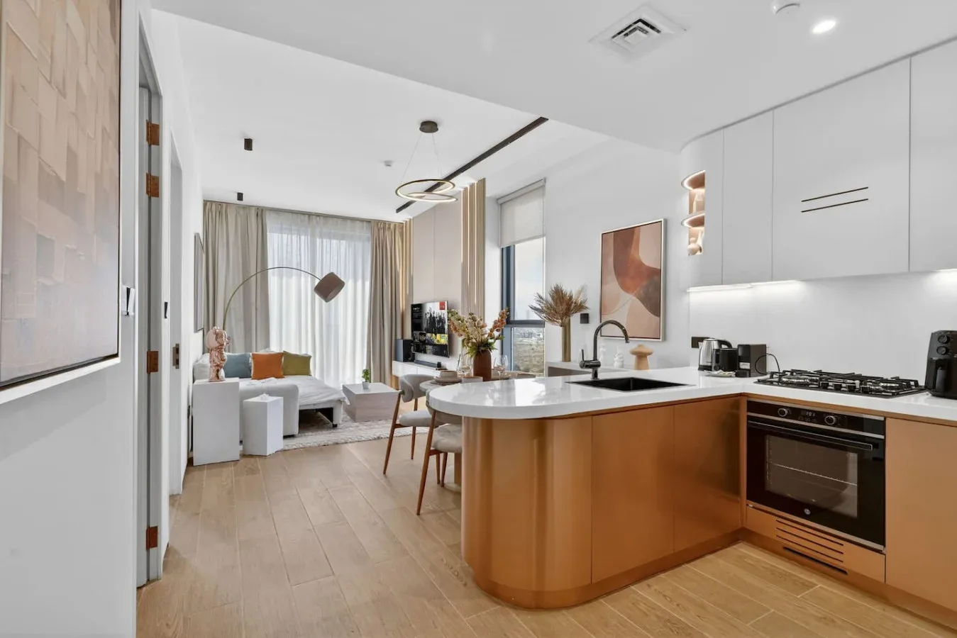 Una cocina y sala de estar de concepto abierto, con una isla curva y una zona de descanso junto a la ventana.