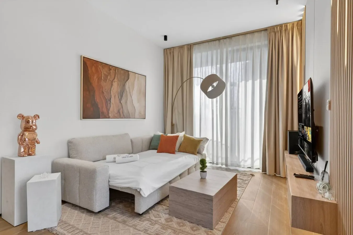 Una sala luminosa con sofá, mesa de centro y cortinas frente a una ventana amplia.