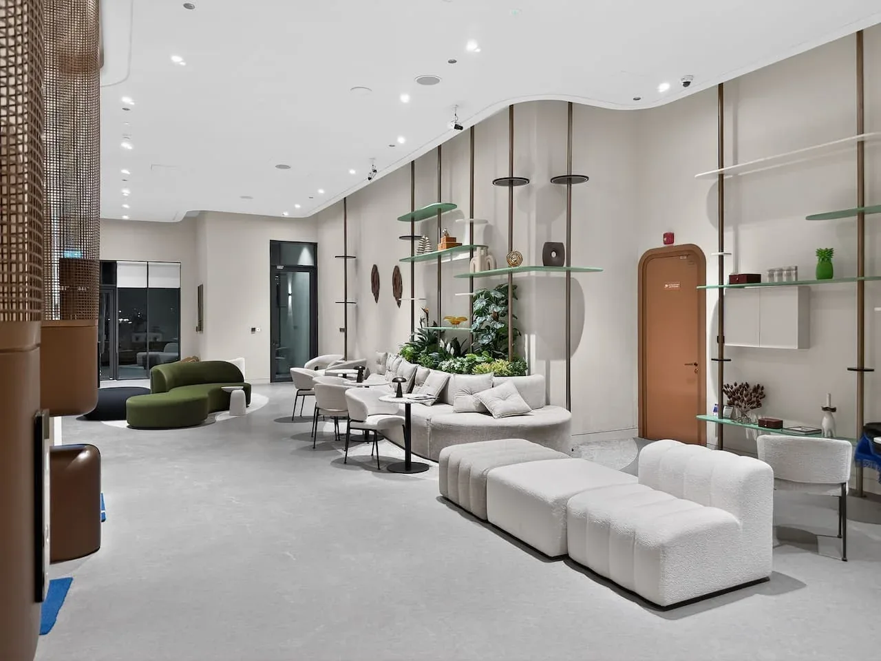Un salón moderno con asientos curvos, mesas bajas y estanterías abiertas.