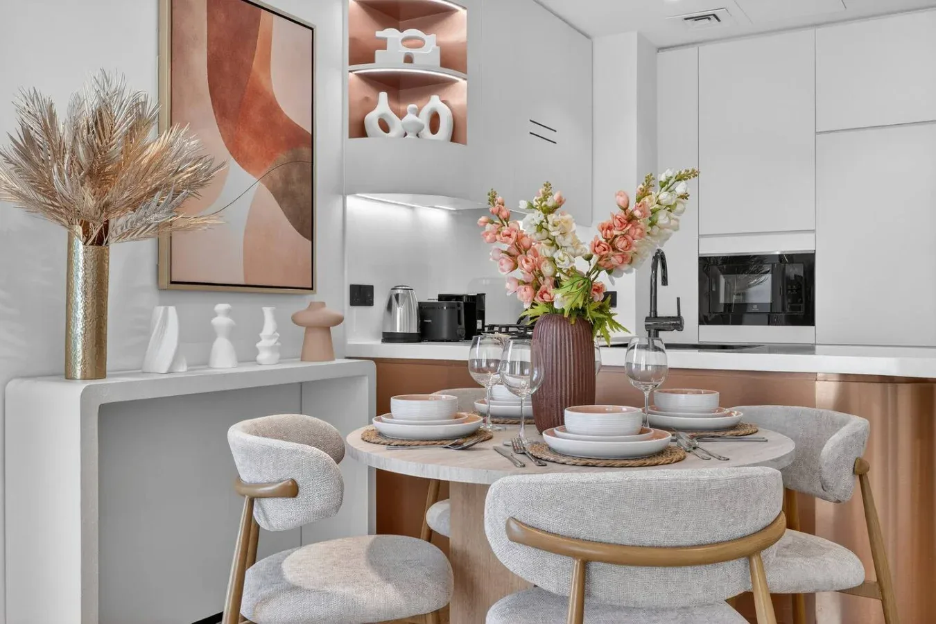 Una mesa de comedor con arreglos florales está junto a una cocina moderna.