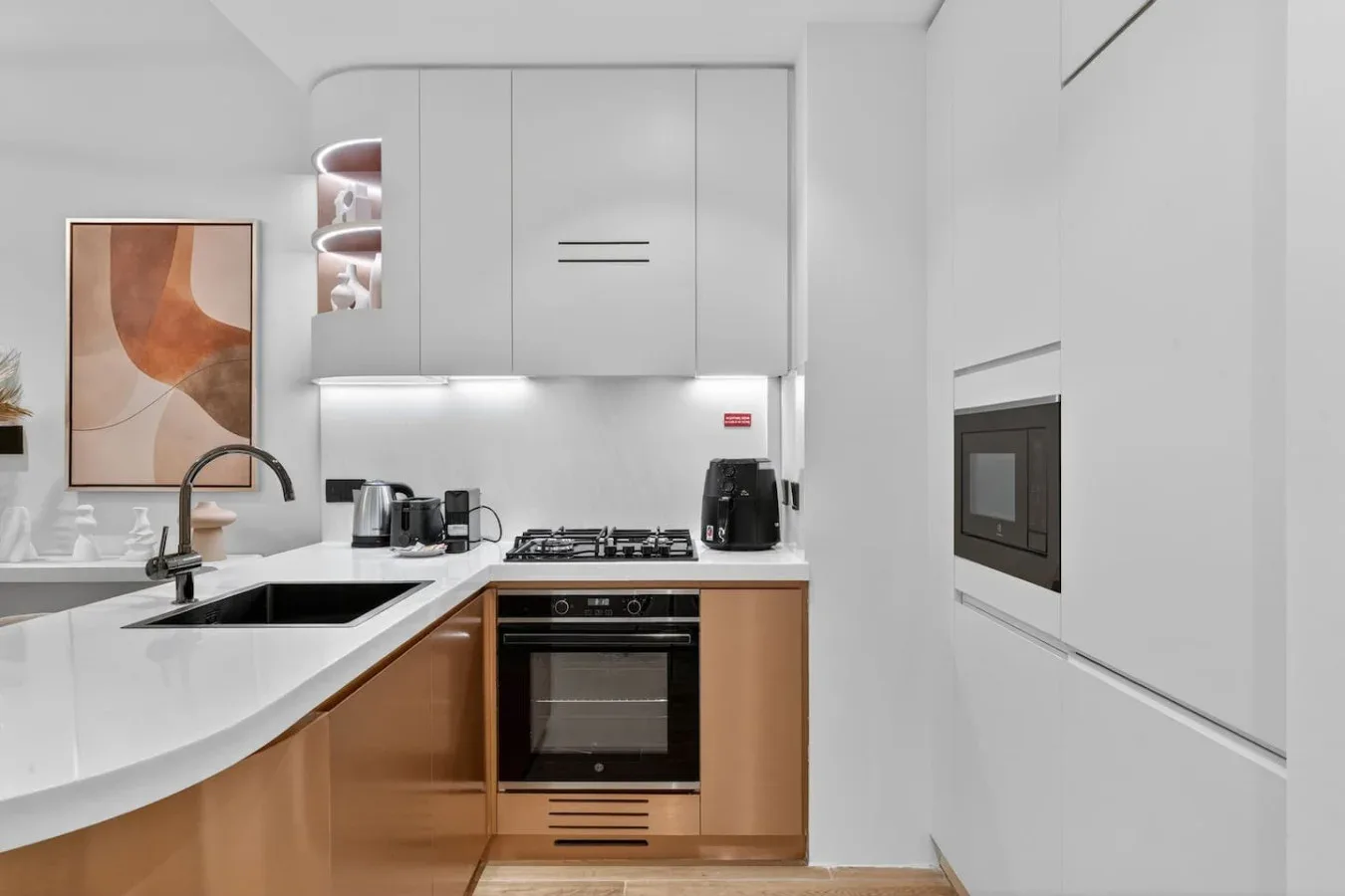 Una cocina moderna con encimeras blancas y electrodomésticos integrados.
