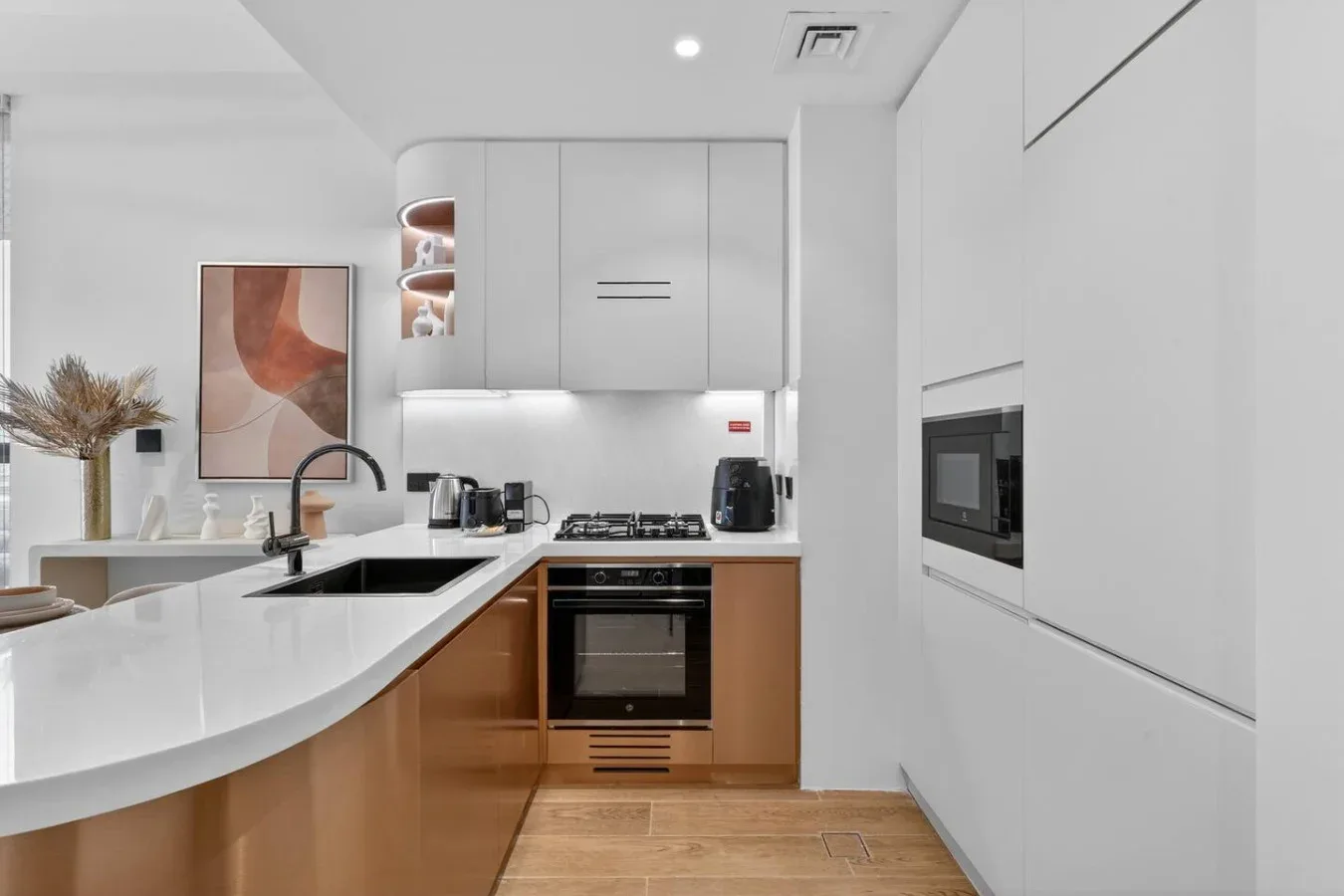 Una cocina moderna con gabinetes blancos, una estufa y una isla curva.