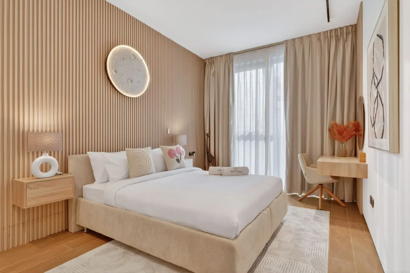 Un dormitorio con una cama tendida, una mesita de noche y una ventana con cortinas.