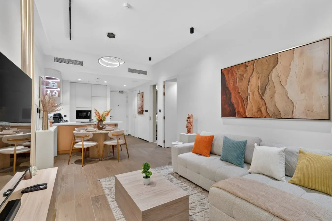 Una luminosa sala-comedor de planta abierta con un sofá claro y una mesa.