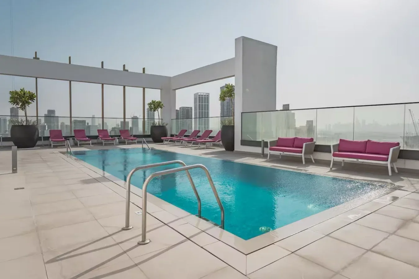 Una piscina en la azotea está junto a asientos y barandillas de vidrio.