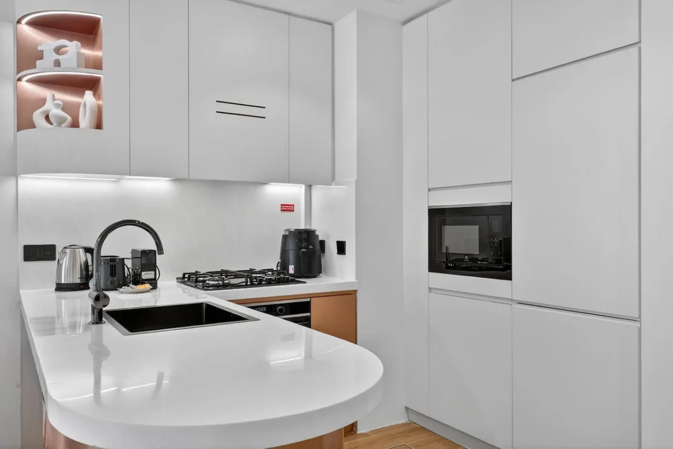 Una cocina moderna con gabinetes blancos y una encimera curva.