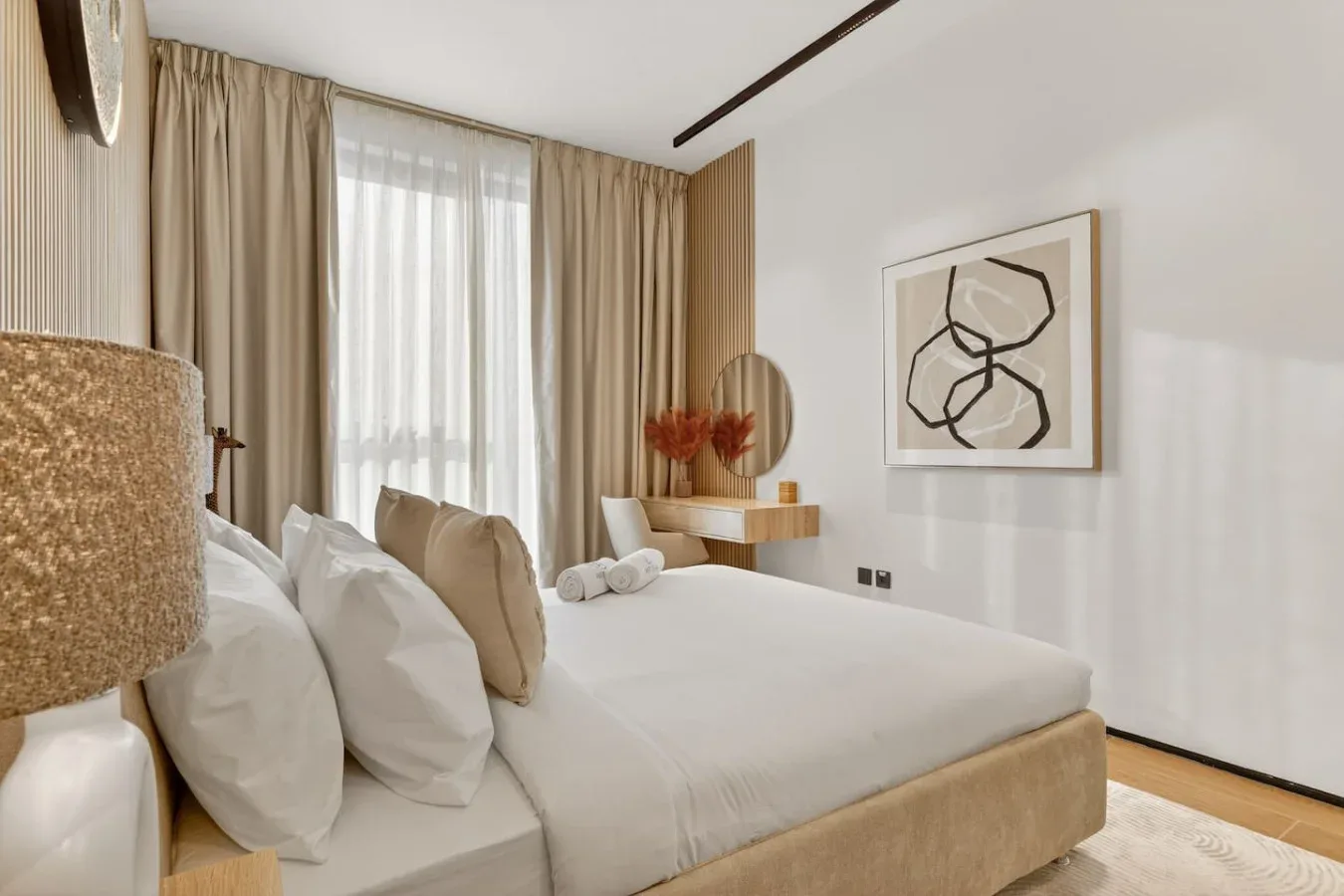Un dormitorio con una cama bien tendida, cortinas altas y arte enmarcado.