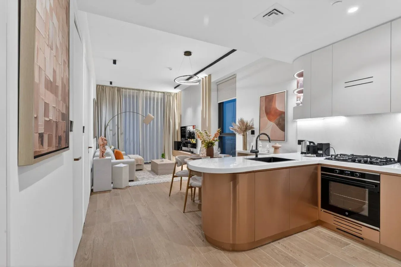Una luminosa cocina abierta al salón, con una isla curva y una mesa de comedor.