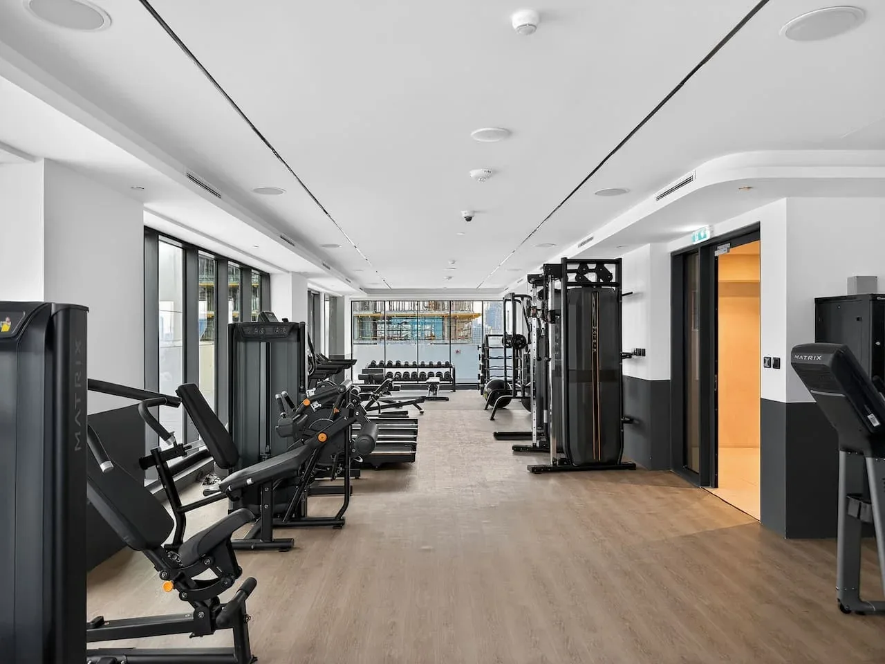 Un gimnasio con máquinas de ejercicio junto a un amplio pasillo central.