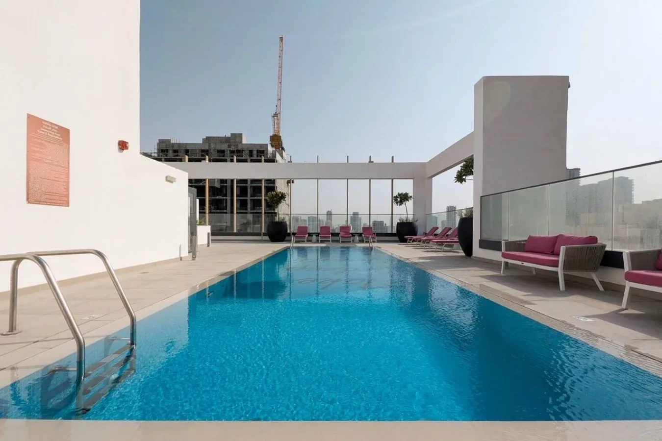 Una piscina en la azotea con asientos y barandillas de vidrio.