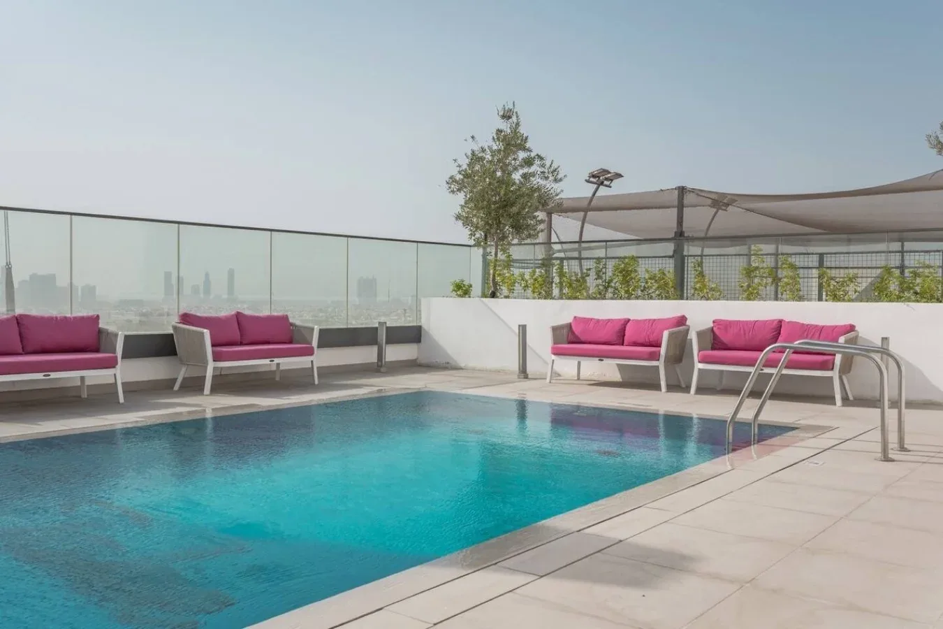 Una piscina en la azotea con asientos rosas alrededor.